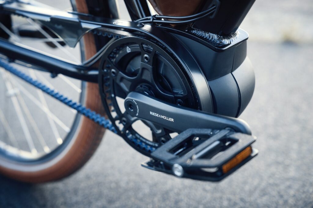 Schwarzer E Bike Antrieb und Pedal mit blauer Kette und braunen Reifen